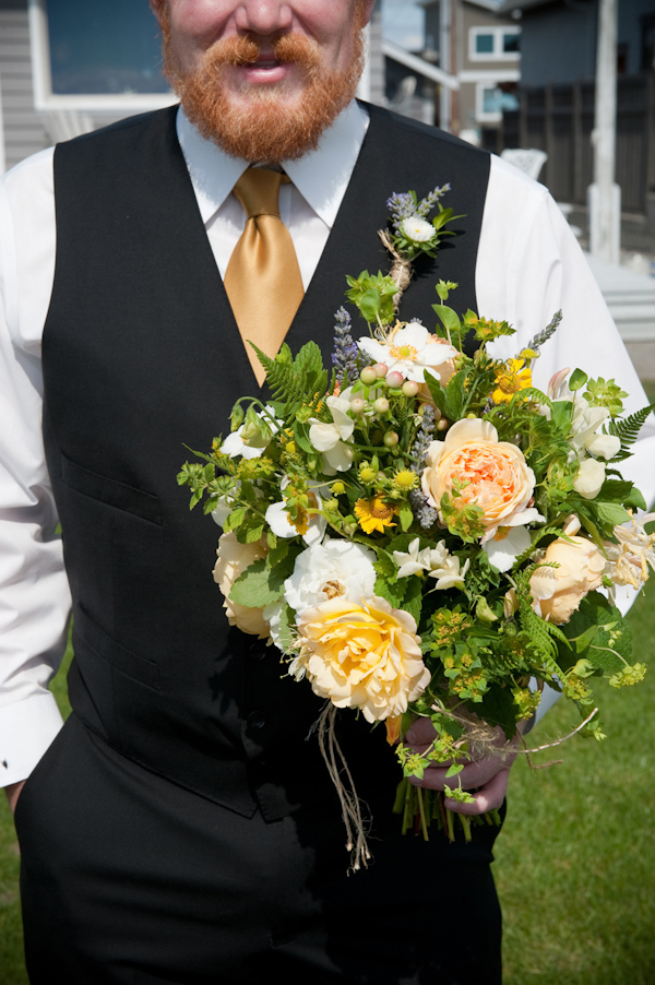 groom wearing black vest and gold tie holding the bride's yellow, white, and green bouquet - photo by Portland wedding photographer Barbie Hull 
